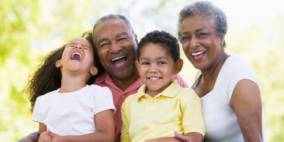 Two black grandparents holding younger children in their arms