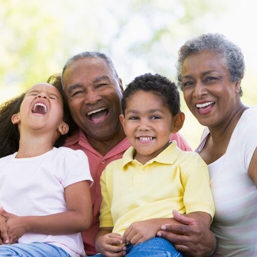 2 black grandparents hugging younger children